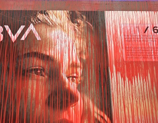 Un cartell del BBVA tacat de pintura vermella en una acció coordinada pel grup antimilitarista de Bilbao KEM-MOC